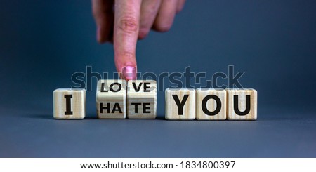 Hand turns cubes and changes the expression 'I hate you' to 'I love you'. Beautiful grey background, copy space. Concept.