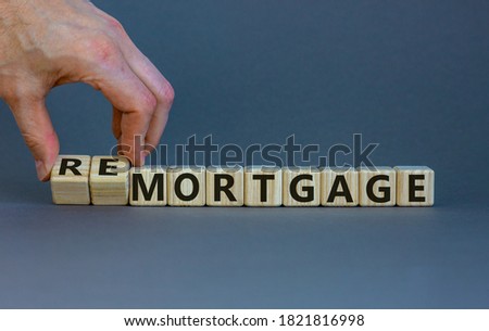 Hand turns cubes and changes the word 'remortgage' to 'mortgage' or vice versa. Beautiful grey background, copy space. Business concept.