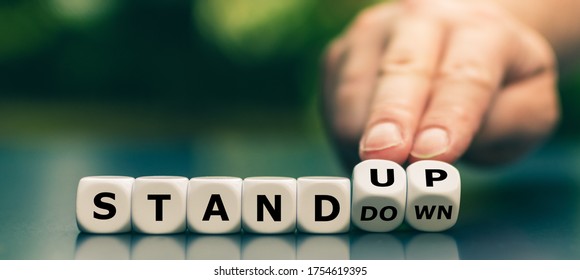 Hand turns dice and changes the expression "stand down" to "stand up". - Shutterstock ID 1754619395