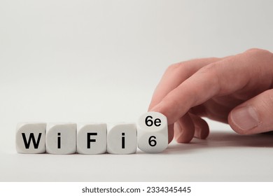 Hand turns dice and changes the expression "WiFi 6" to "WiFi 6e" on white background 
					