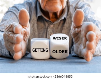 Hand turns dice and changes the expression 'getting older' to 'getting wiser' in front of an old man.	