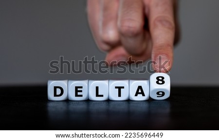 Hand turns dice and changes the expression 'delta 9' to 'delta 8'. Symbol for the Delta-8-tetrahydrocannabinol, a psychoactive cannabinoid found in the Cannabis plant.