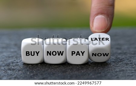 Hand turns dice and changes the expression 'buy now pay now' to 'buy now pay later'.