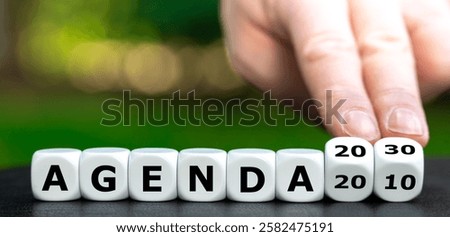 Hand turns dice and changes the expression 'agenda 2010' to 'agenda 2030'.