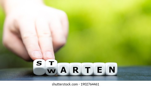 Hand turns dice and changes the German word "warten" (wait) to "starten" (start).