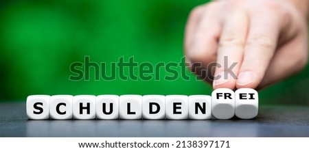 Hand turns dice and changes the German expression 'Schulden' (debt) to 'Schuldenfrei' (debt free). Stock foto © 