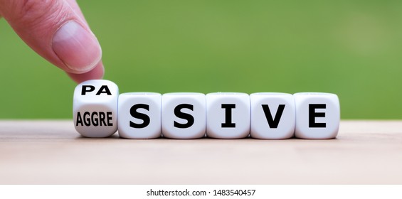 Hand turns a dice and changes the word "passive" to "aggressive", or vice versa. - Shutterstock ID 1483540457