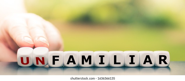 Hand turns dice and changes the word "unfamiliar" to "familiar". - Shutterstock ID 1636366135