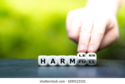 Hand turns dice and changes the word "harmful" to "harmless". - Shutterstock ID 1839121531