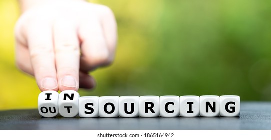 Hand turns dice and changes the word outsourcing to insourcing.