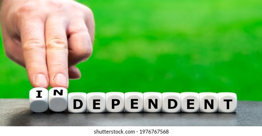 Hand turns dice and changes the word "dependent" to "independent". - Shutterstock ID 1976767568