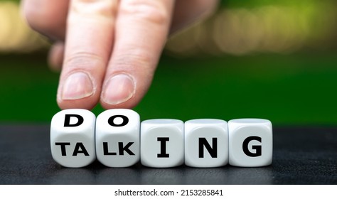 Hand turns dice and changes the word talking to doing.