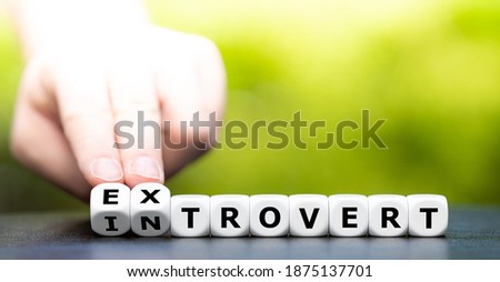 Hand turns dice and changes the word introvert to extrovert.