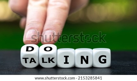 Hand turns dice and changes the word talking to doing.