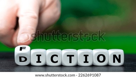 Hand turns dice and changes the word diction to fiction.
