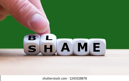 Hand turns dices and changes the word "Shame" to "Blame"
