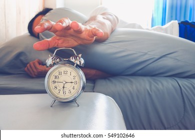 Hand turns off the alarm clock waking up at morning . soft skin tone effect