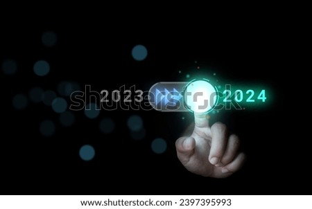 Hand turns on the switch, moving from 2023 to 2024. The idea of ​​entering the new year with modern technology.