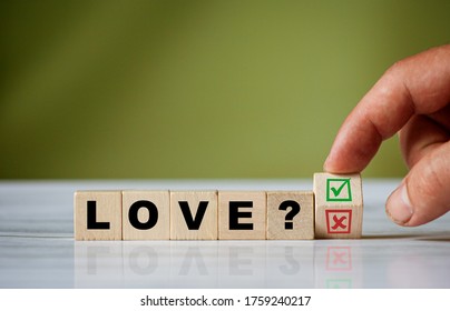 The hand turns the wooden cube and changes the word LOVE with green positive tick check box and red reject X check box. - Shutterstock ID 1759240217