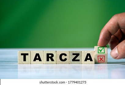 The hand turns the wooden cube and changes the polish word TARCZA (english shield) with green positive tick check box and red reject X check box. - Shutterstock ID 1779401273