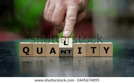 Hand turns wooden cube and changes the word quantity to quality.