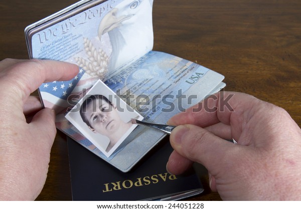 Hand with tweezers holding id photo over\
passport as if forging the travel\
documents