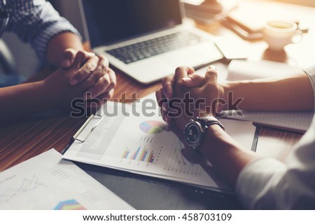 Hand, two men on a desk. Negotiating business.