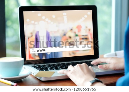 Hand tying labtop computer with www. on search bar over blur store background on screen, on line shopping ,business, E-commerce, technology and digital marketing concept background