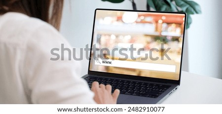 Hand tying labtop computer with www. on search bar over blur store background on screen, on line shopping ,business, E-commerce, technology and digital marketing concept background