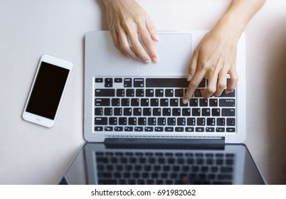 Hand typing on  computer keyboard. 
phone next to it. Business and Technology Concepts