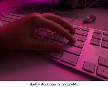 hand typing on white keyboard, illuminated by pink lighting fingers are pressing the return key, with nearby keys including shift control, option delete Earbuds technology setup programmer haker - Powered by Shutterstock