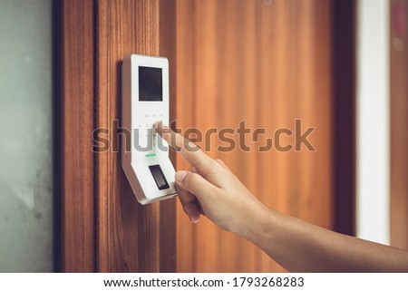 hand typing password at electronic door lock and security system panel.