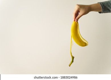 Hand Of Unknown Caucasian Woman Holding Banana Peel In Front Of White Wall - Copy Space Concept Of Ending And Finish Trash Ready To Be Thrown Away Old Habit And New Beginning