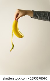 Hand Of Unknown Caucasian Woman Holding Banana Peel In Front Of White Wall - Copy Space Concept Of Ending And Finish Trash Ready To Be Thrown Away Old Habit And New Beginning