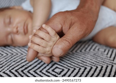 Hand of unrecognizable senior man and little sleeping baby closeup, grandfather holding newborn baby hand while his grandchild sleeping - Powered by Shutterstock