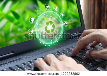 Hand use laptop computer with environment Icons over the Network connection on nature background, Technology ecology 
concept.