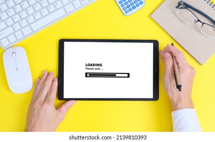 Hand used tablet with concept of improving website loading speed, Top view office stuff with notepad, laptop and mouse, notepad blank screen and supplies on white desk workspace and copy space.