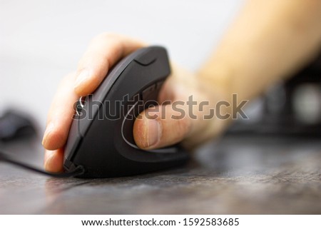 man’s hand uses a vertical ergonomic computer mouse-joystick.