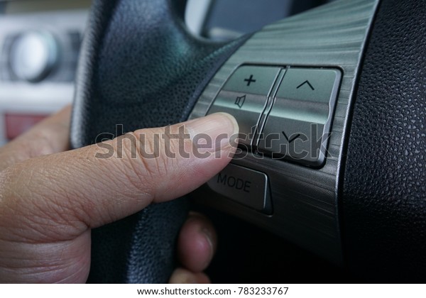 hand using audio system controller button\
on steering wheel to decrease sound volume\
