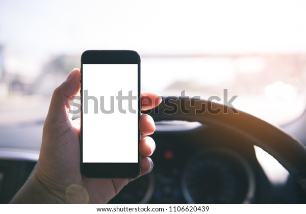 Hand\
using blank white screen mobile smartphone inside a car in sunny\
day, copy space for your app or product\
display,