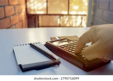Hand Using Calculator Next to Notebook on Office Desk, financial concept
