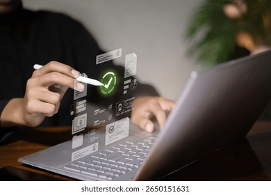 Hand using digital pen to verify online documents with holographic interface on laptop, representing secure digital process and technology.