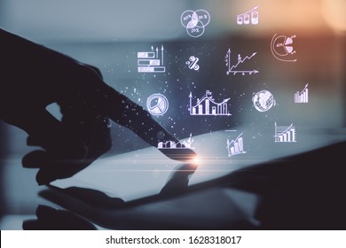 Hand using digital tablet with glowing creative forex chart on blurry desktop backround. Finance and trade concept. Close Up