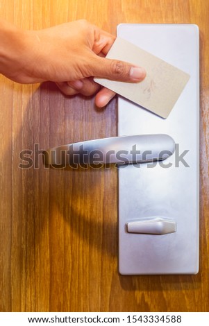 Hand using electronic smart contactless key card for unlock door in hotel or house.