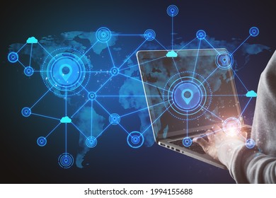 Hand using laptop with abstract map and location pins hologram on blue background. Geolocation and globalization concept