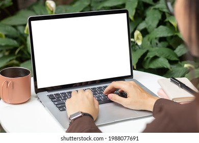 Hand using laptop computer with blank white screen on desk. 