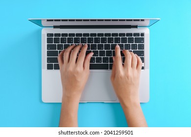 hand using laptop computer on blue background top view