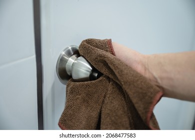 Hand Using Microfiber Cloth Wiping Doorknob In Bathroom