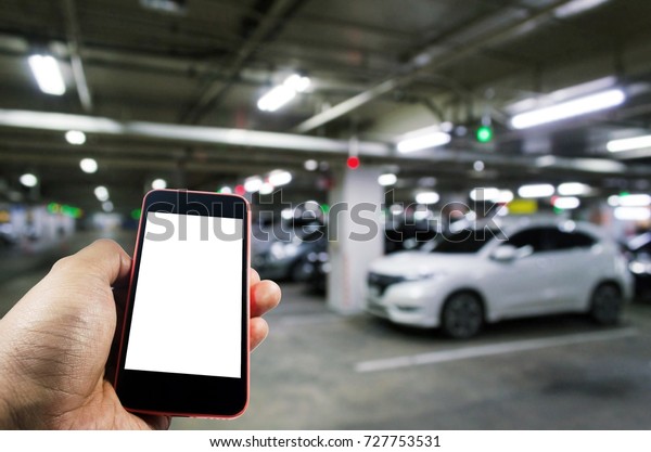 hand\
using mobile smart phone with blurred image of indoor car parking\
garage area, RFID solution management system, internet, social\
media and car parking sensor technology\
concept