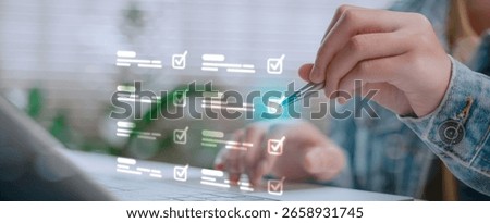 Hand using pen to check virtual checklist on laptop screen. Concept of task management, digital workflow, productivity, project planning, and online organization system.